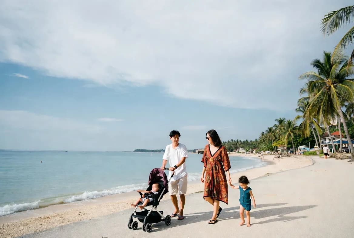 Happy family walking along the calm, stroller-friendly beach path in Sanur, Bali